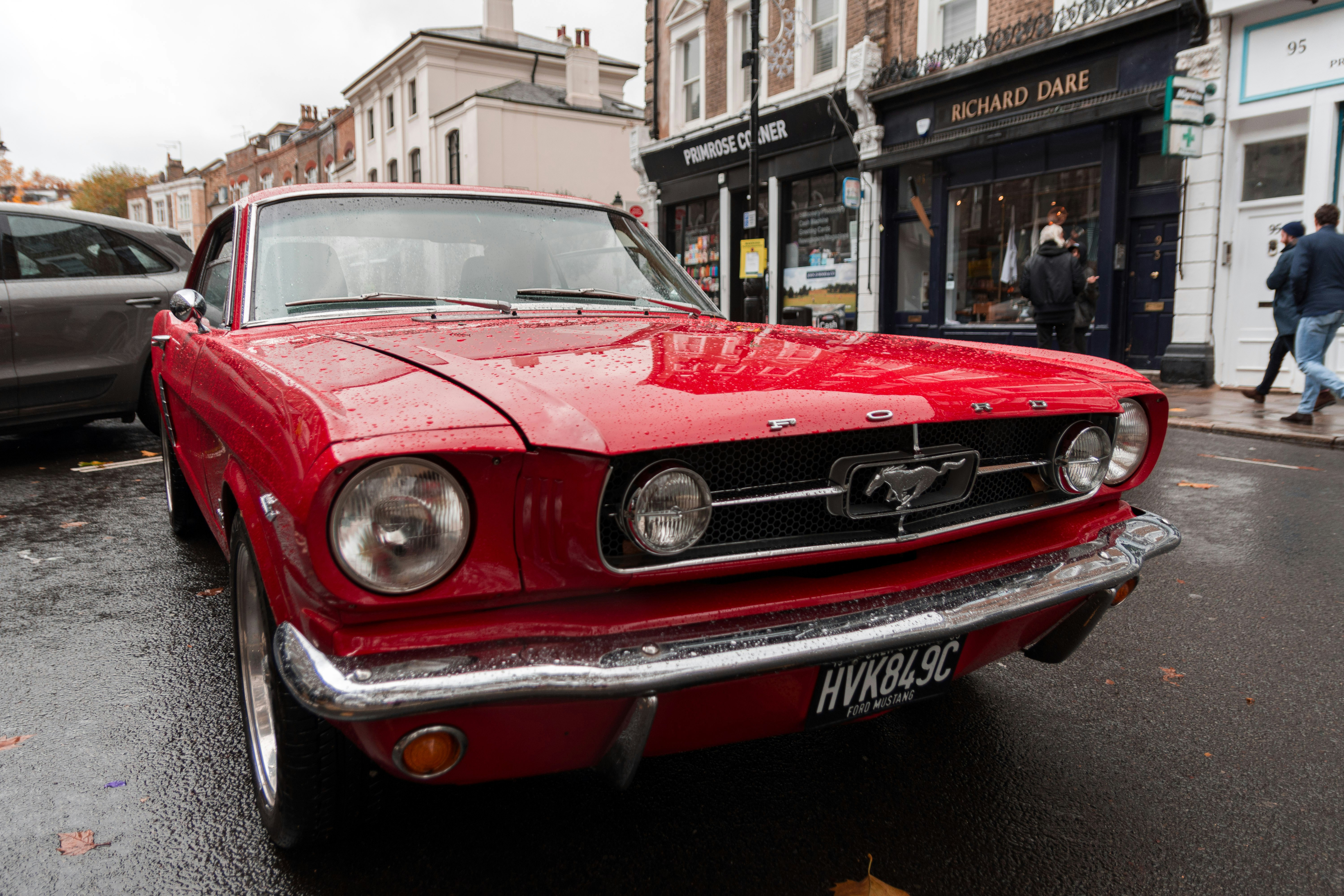 red first generation Ford Mustang coupe parking near road